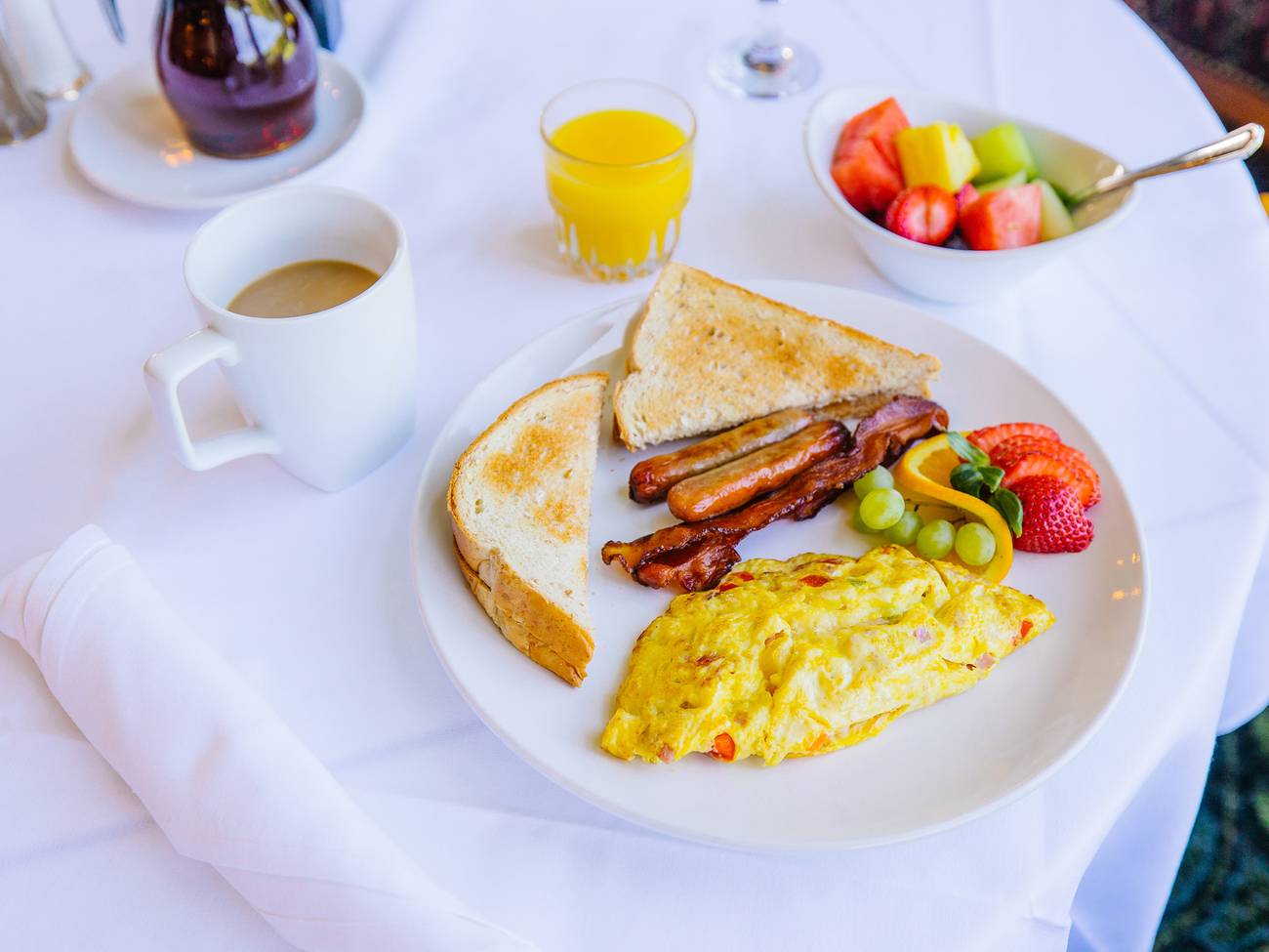 A breakfast platter of eggs, toast, fruit, and bacon