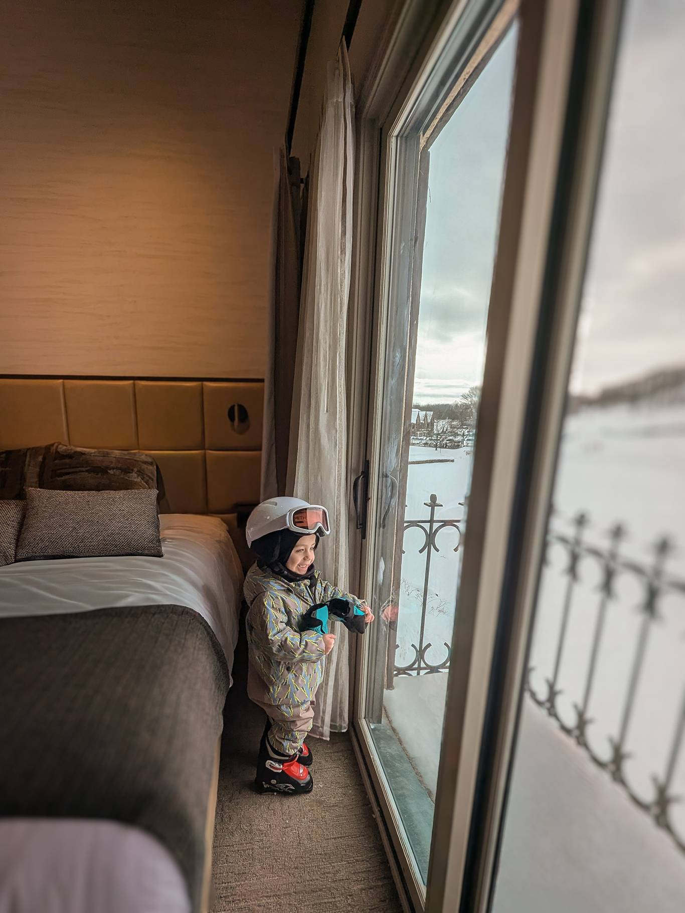 A kid in ski gear staring out the window in the Main Lodge
