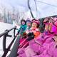 A group of kids in ski gear on the Camelot 6 chairlift at The Highlands